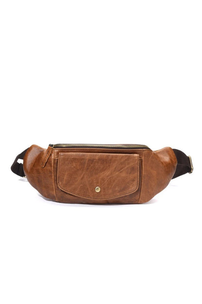 Side view of the closed tan vegetable-tanned leather crossbody chest bag on a white background
